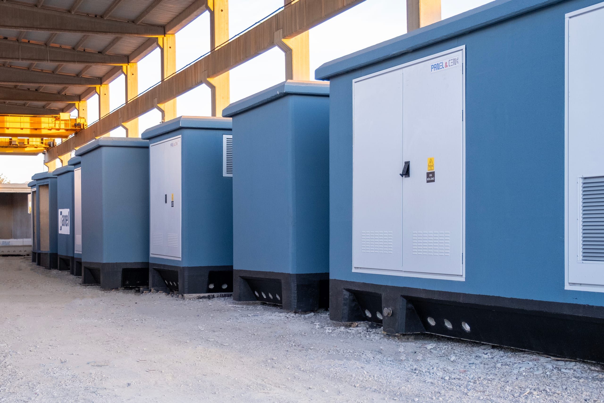 Monobloc concrete transformer kiosks lined up under the gantry crane in the production yard